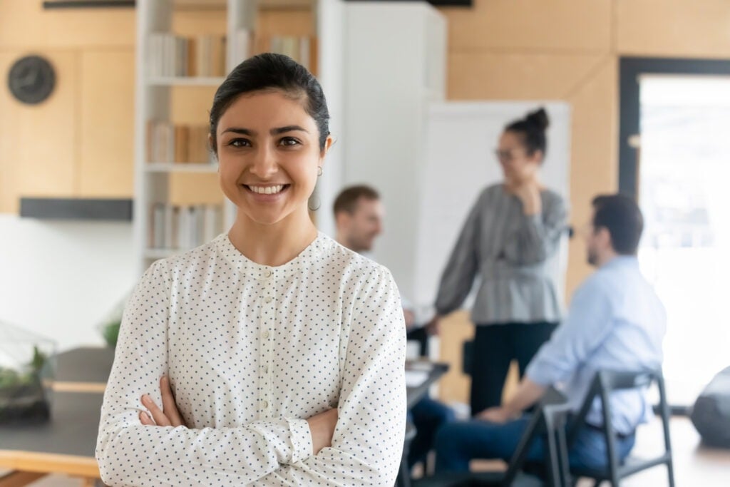 head shot portrait smiling confident indian businesswoman with arms crossed