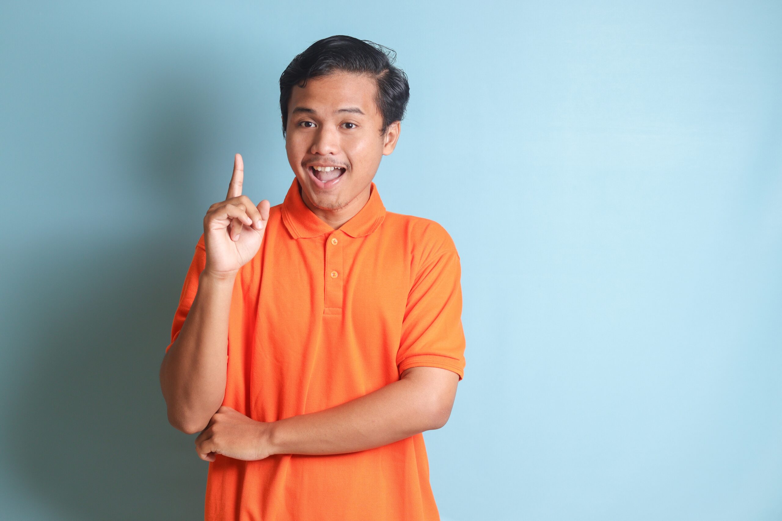 portrait,of,cheerful,asian,man,in,orange,shirt,standing,against